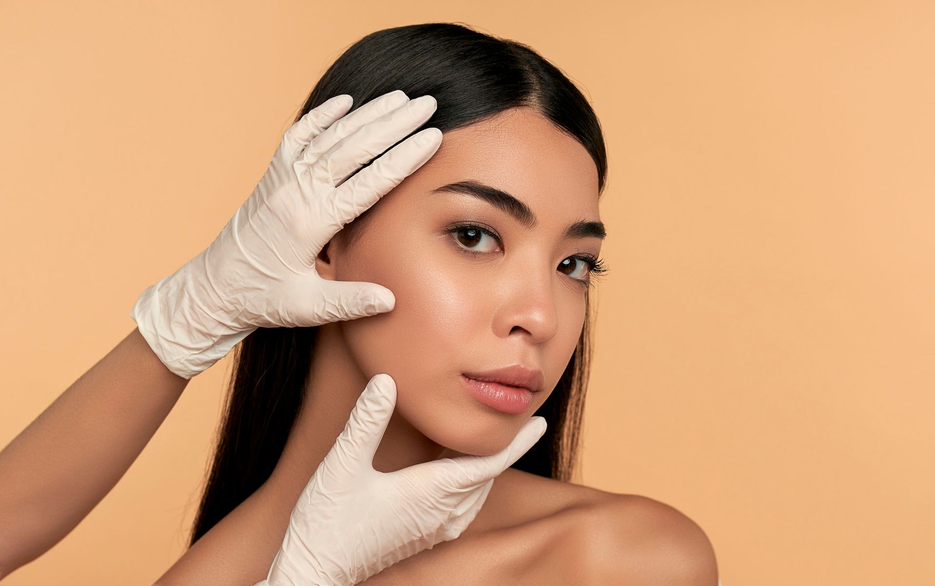 A woman is getting her face examined by a doctor wearing gloves. A woman is getting her face examined by a doctor wearing gloves.