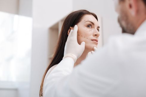 Doctor examining a patient’s face in a bright clinic room