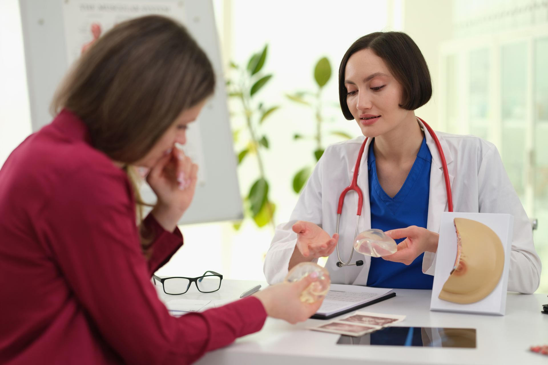 Doctor explaining a medical model to a patient at a desk in a bright clinic