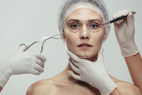 Close-up of a woman during a facial procedure, with gloved hands applying tools near her face.