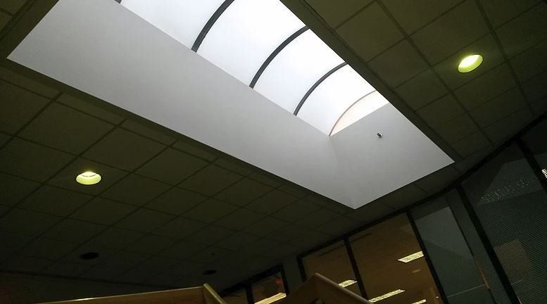 Ceiling with a long rectangular skylight and recessed lighting.