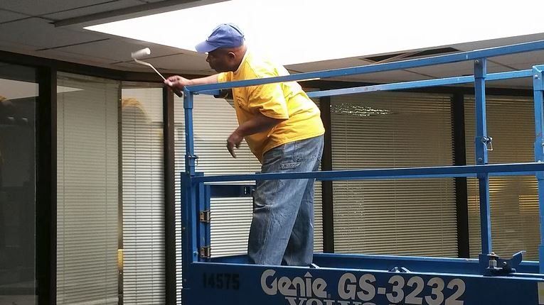 Man painting ceiling from a Genie GS-3232 lift platform.