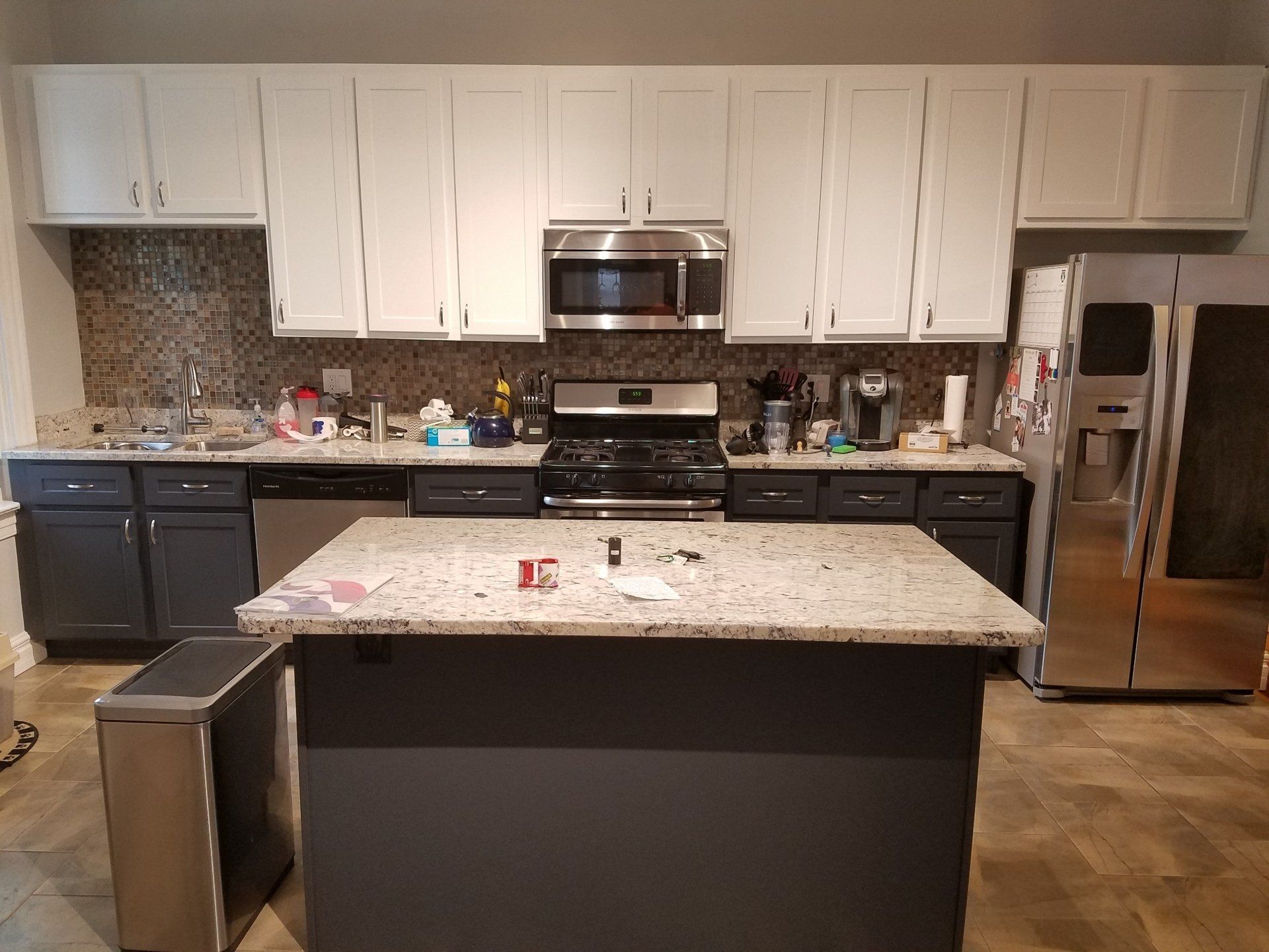 Kitchen with white upper cabinets, dark gray lower cabinets, granite countertops, and stainless steel appliances.
