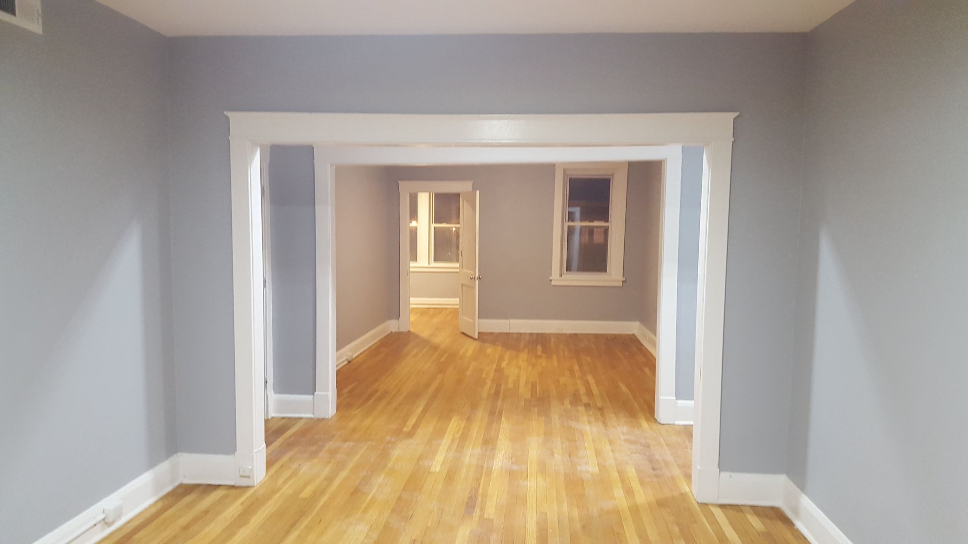 Empty room with light blue walls, white trim, and hardwood floors.