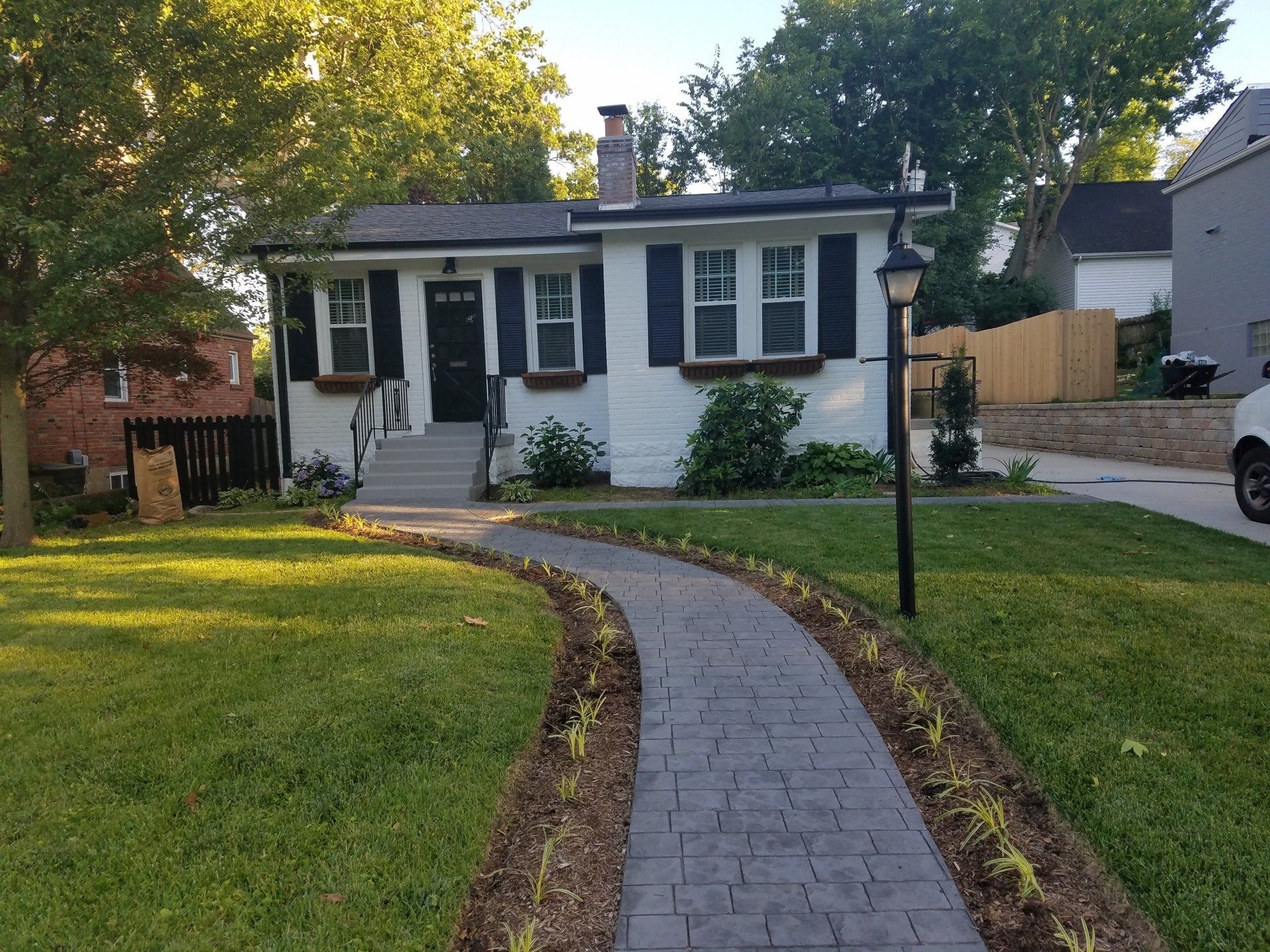 A white house with black shutters and a patterned walkway leading to the front door.