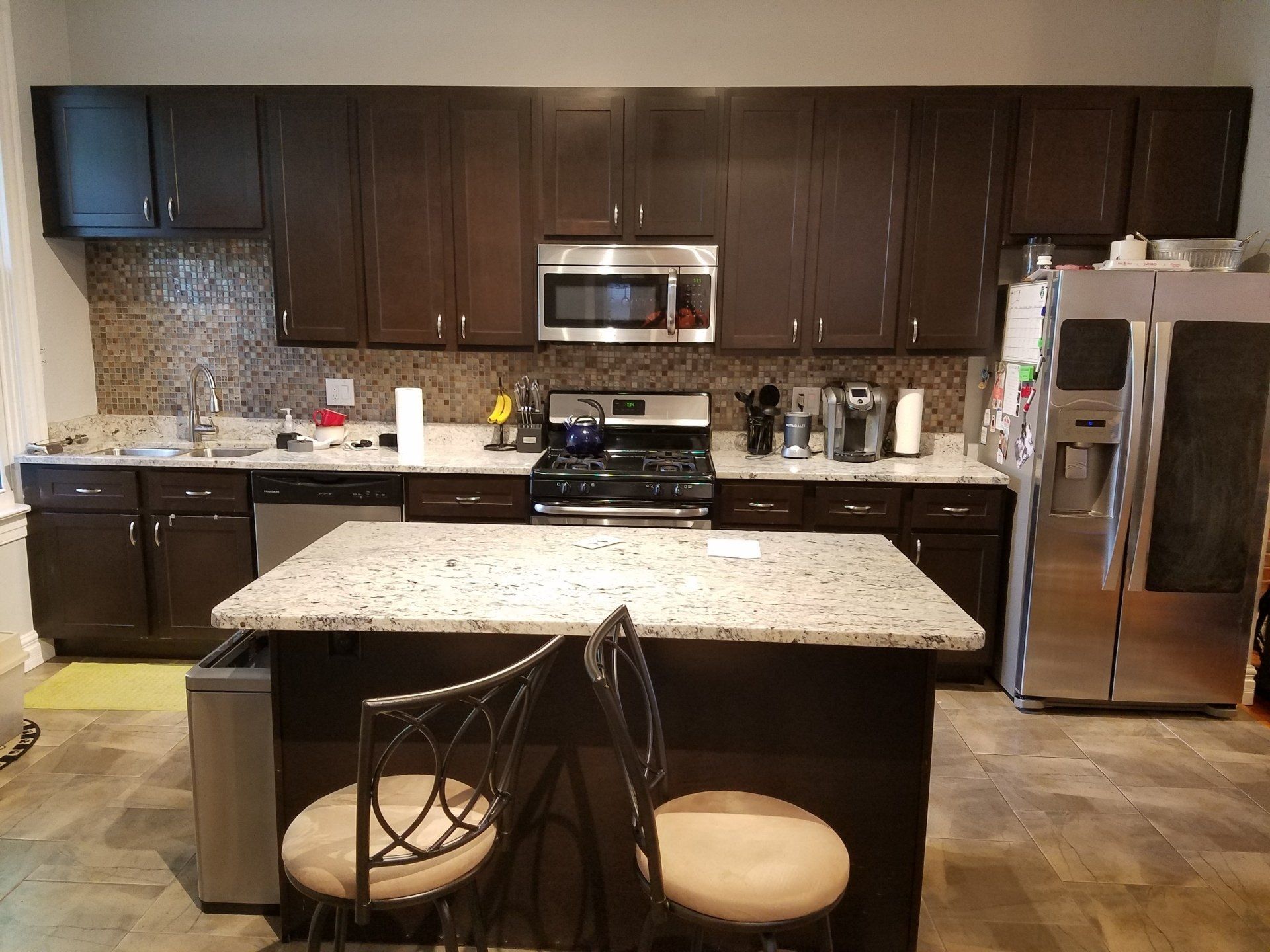 Kitchen with dark brown cabinets, stainless steel appliances, and a granite countertop island.
