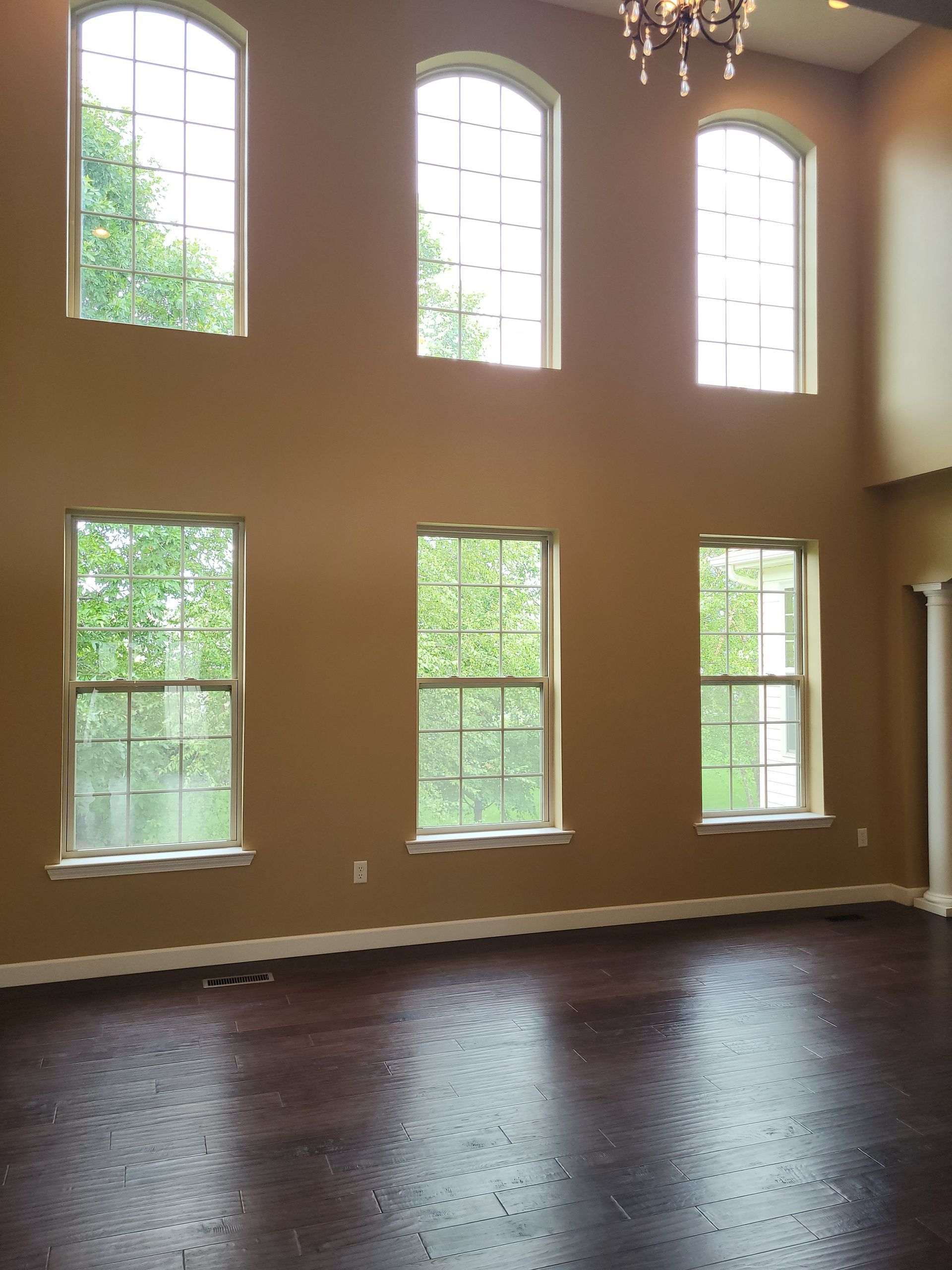 Interior view of a room with six windows, dark flooring, and tan walls.