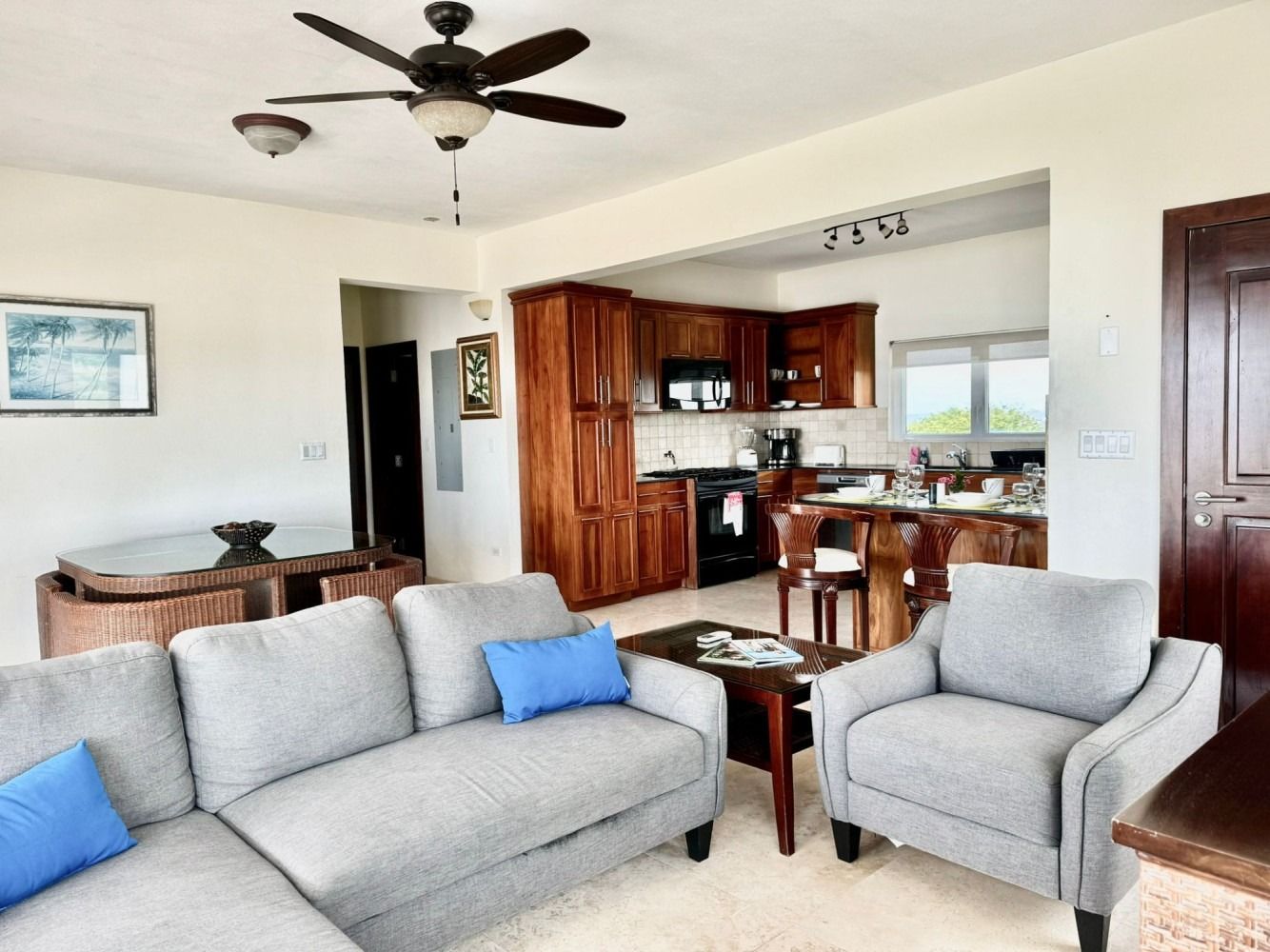 Living room with a gray couch, wooden furniture, and an open kitchen.