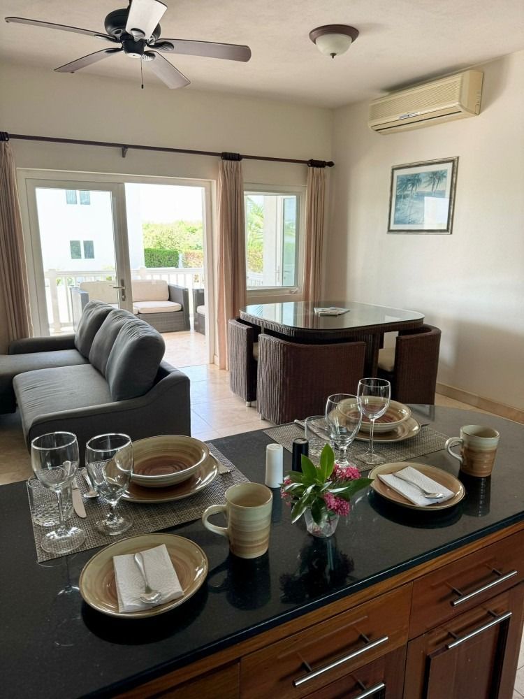 Kitchen with dining area and sofa. Table set with dishes; sliding glass door opens to patio.