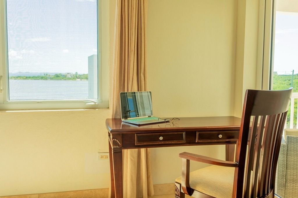 Desk with laptop, chair, and window overlooking water.