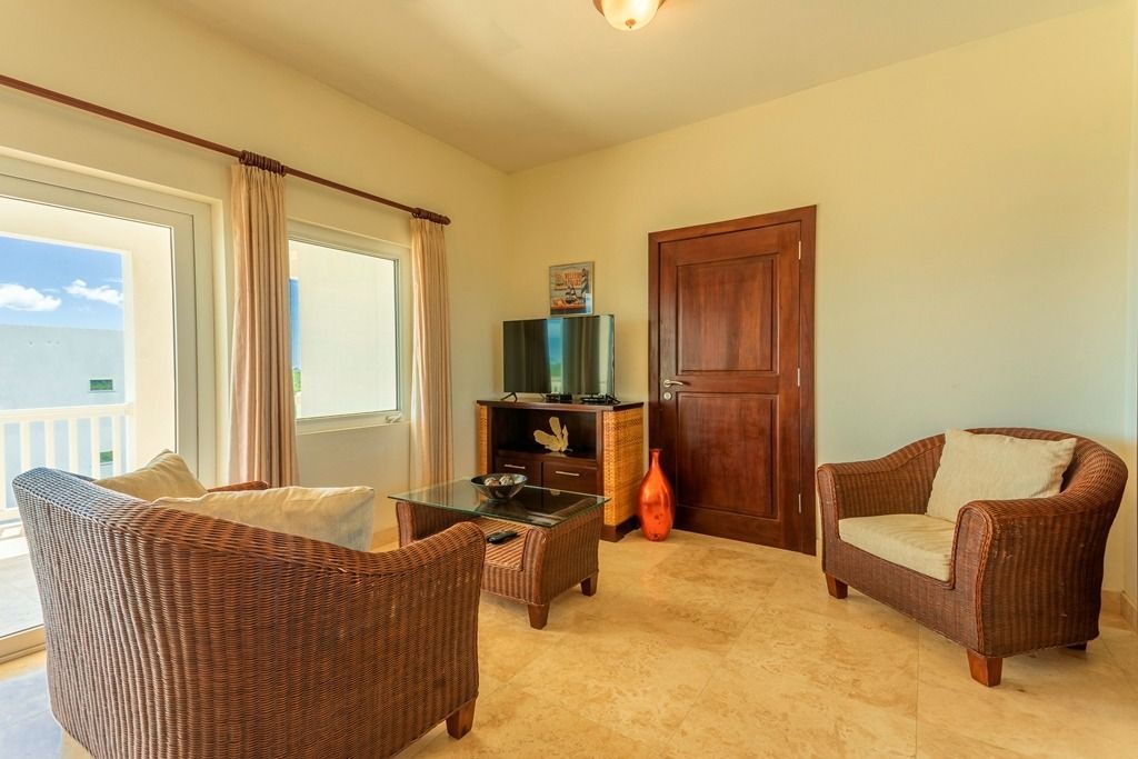 Living room with wicker furniture, TV, and door leading to a balcony.
