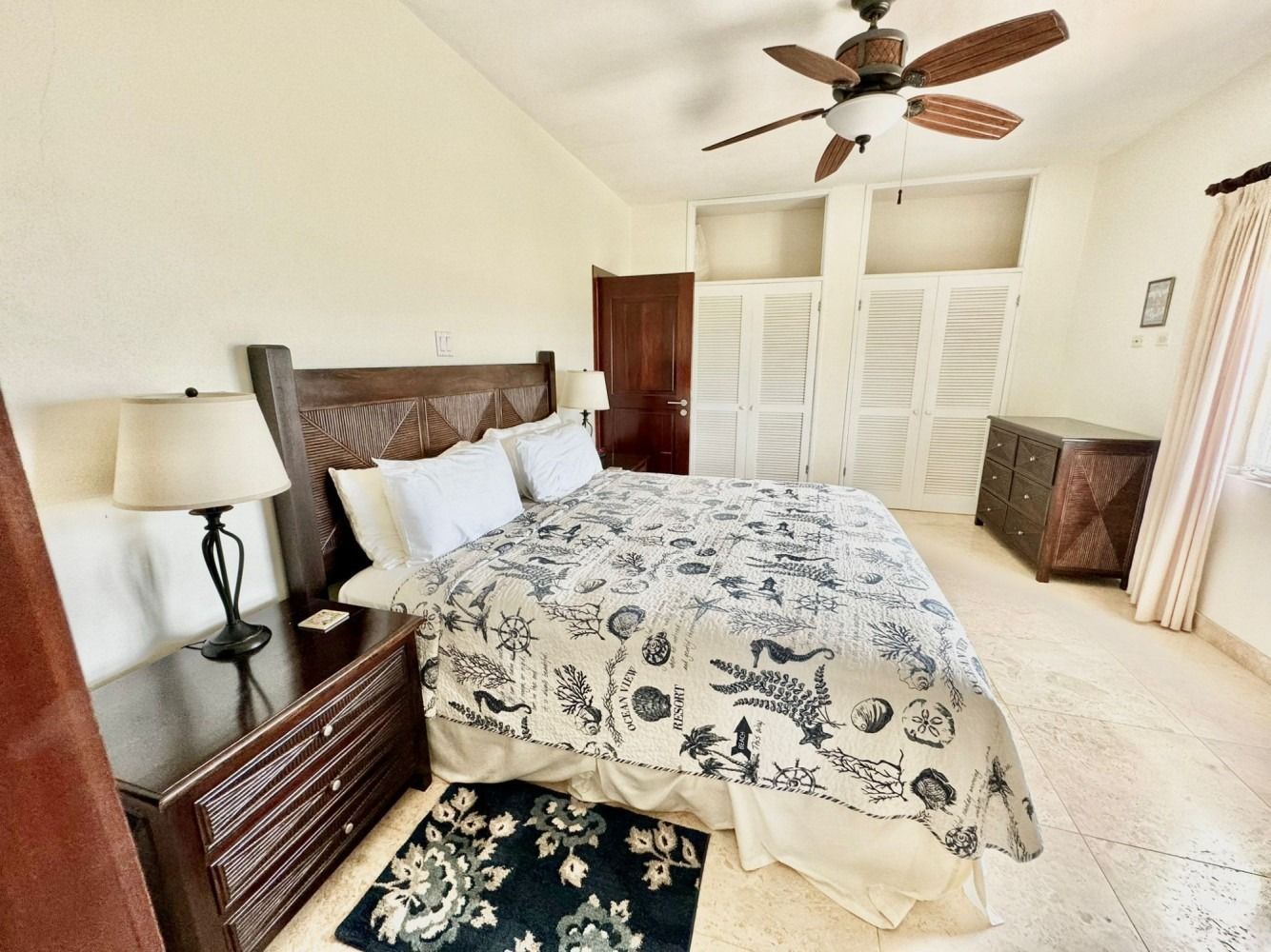 Bedroom with bed, nightstands, dresser, shuttered closet, and ceiling fan.