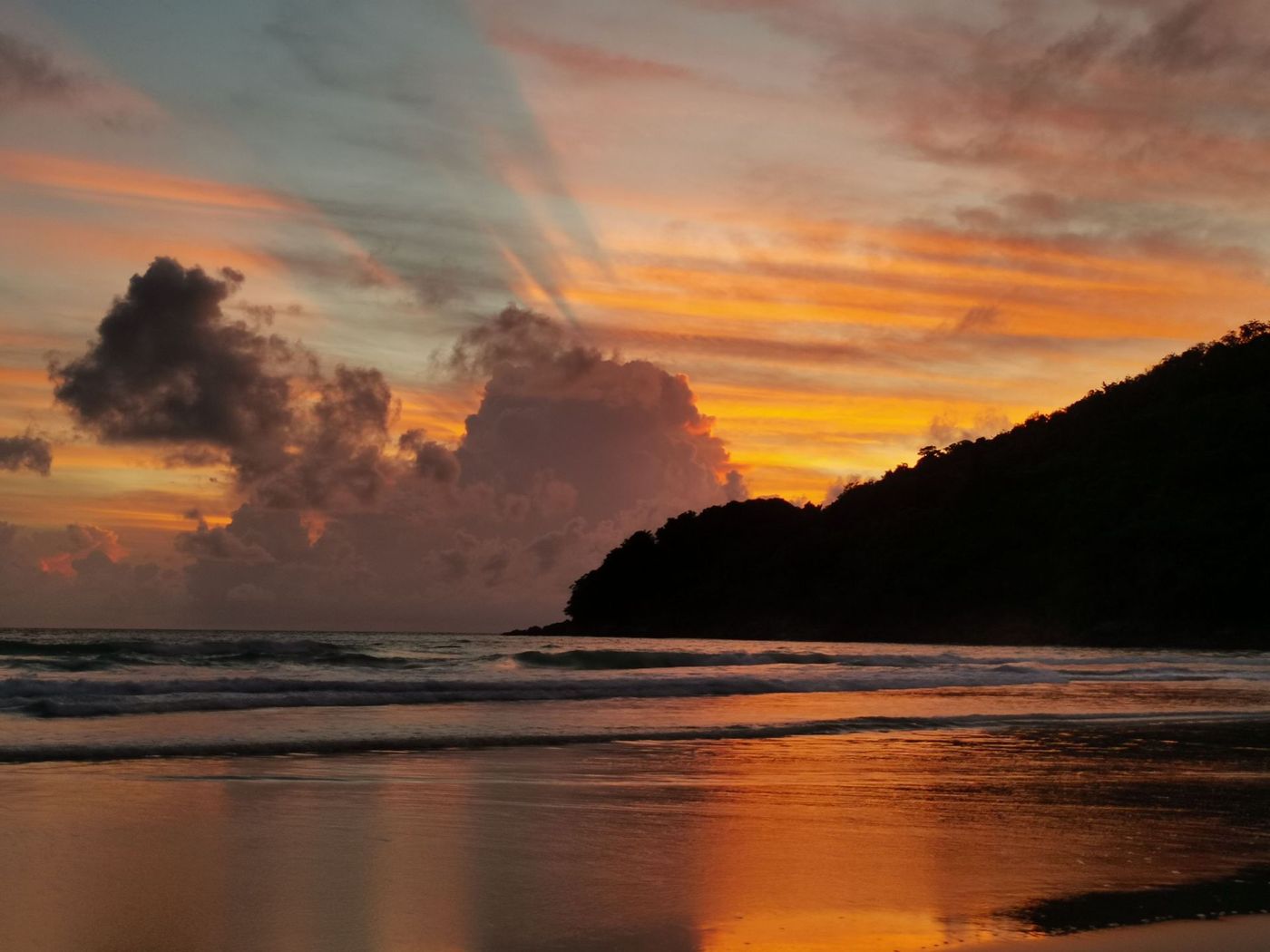 Sunset over a calm beach with orange and purple clouds отражаются on wet sand