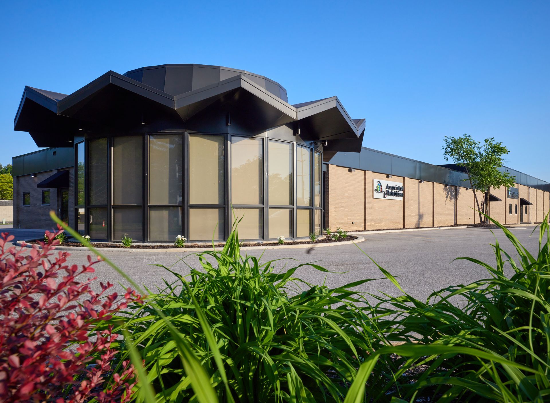 A large building with a lot of windows is surrounded by plants