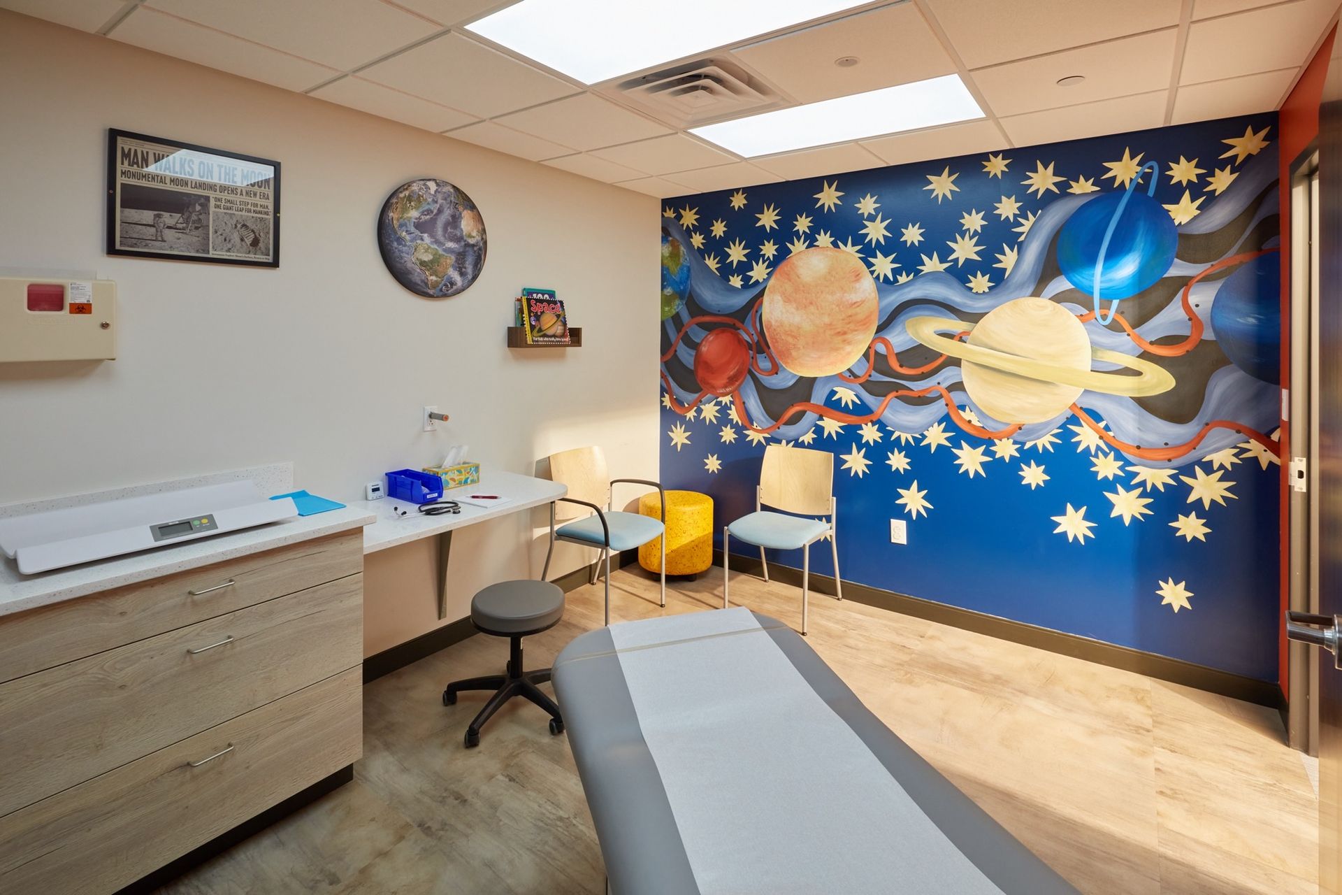 A pediatrician's office with a mural of the solar system on the wall.