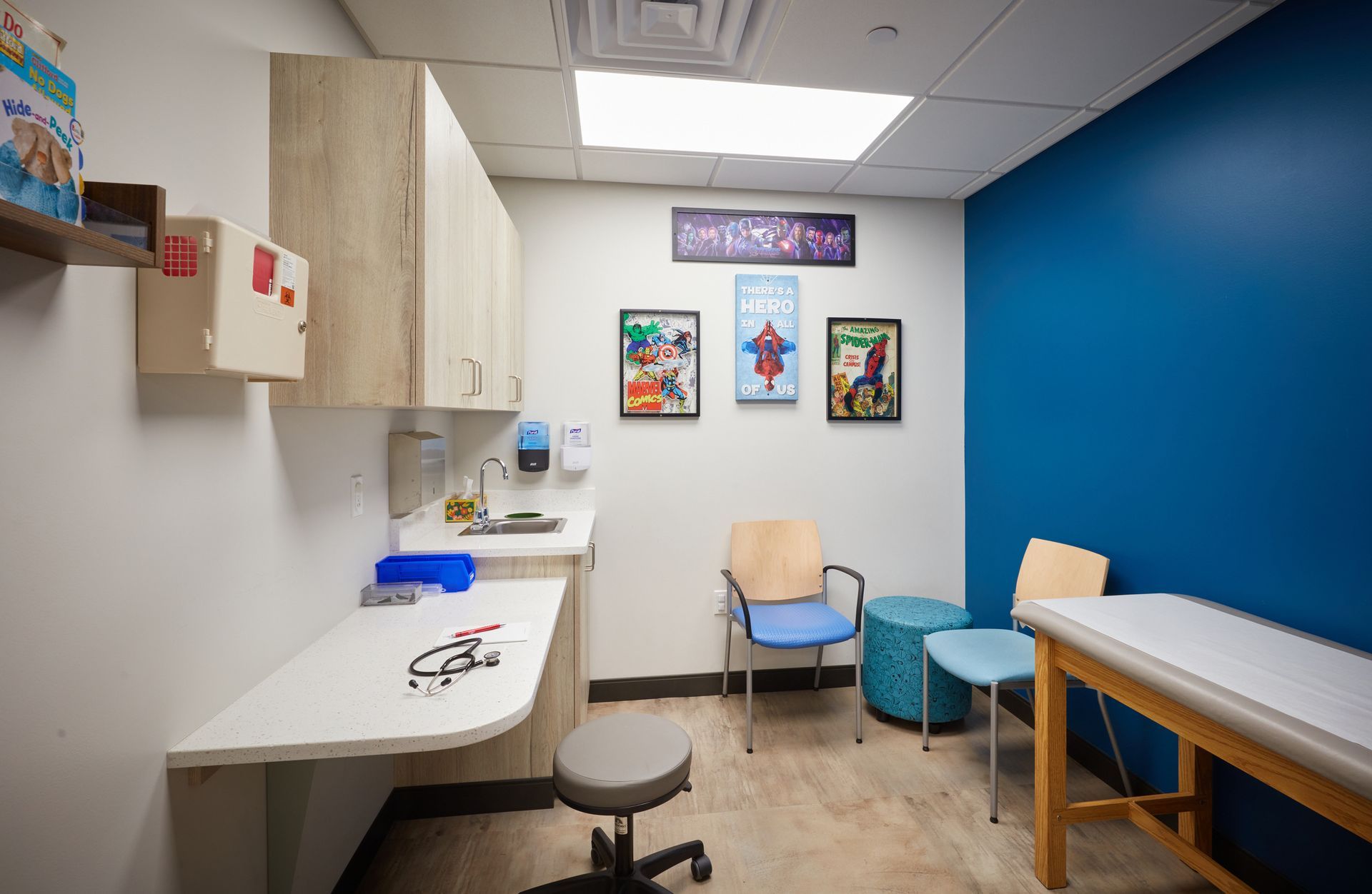 A pediatrician's office with a table and chairs and a blue wall.