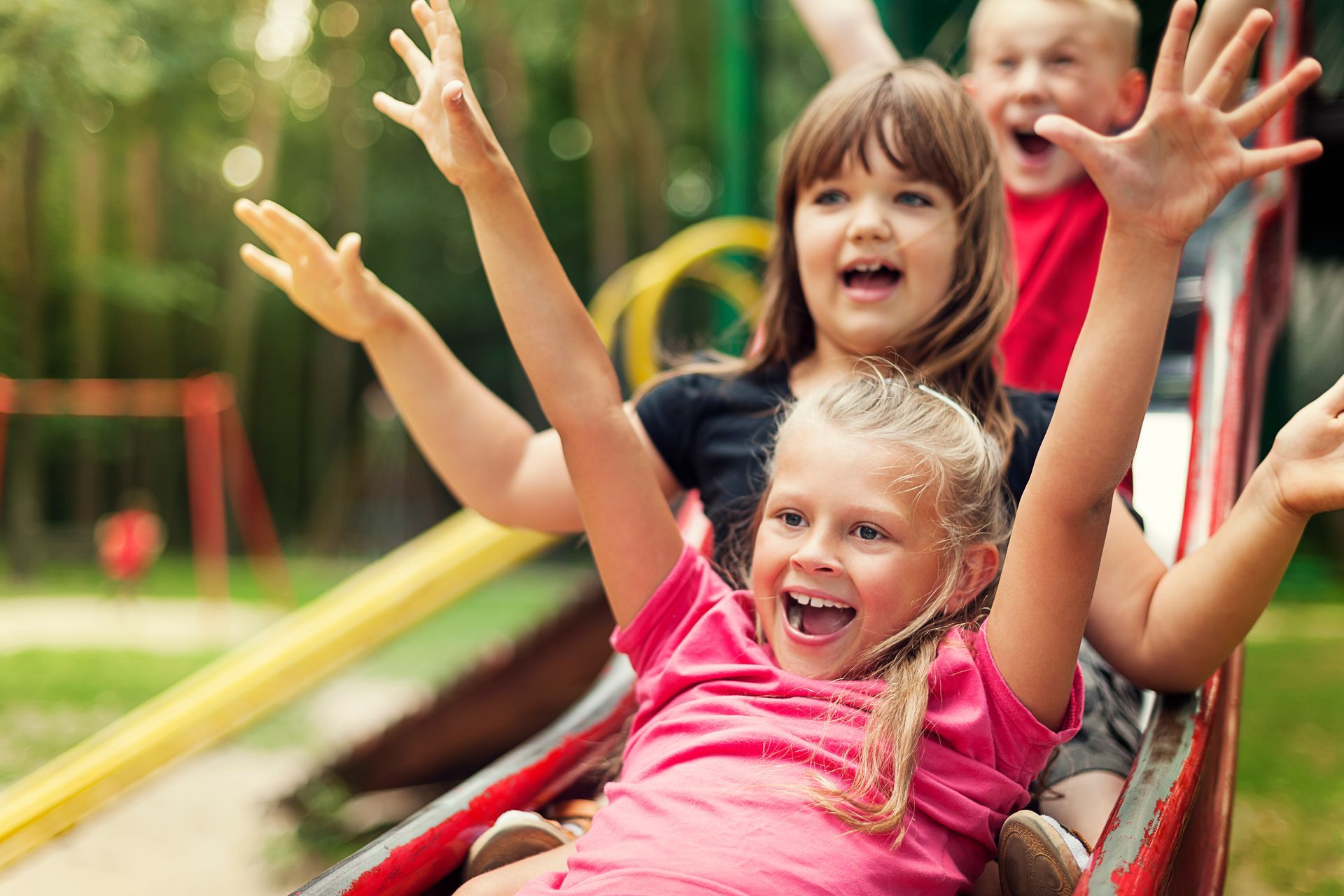 A group of children are riding down a slide at a playground.