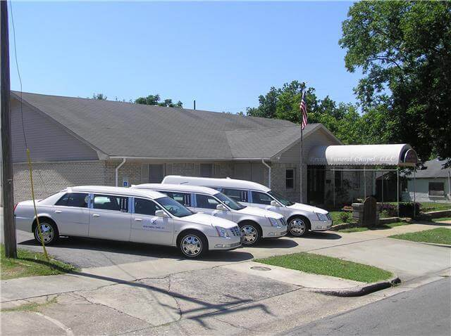Silver cars parked outside a small building with a covered entrance on a sunny day