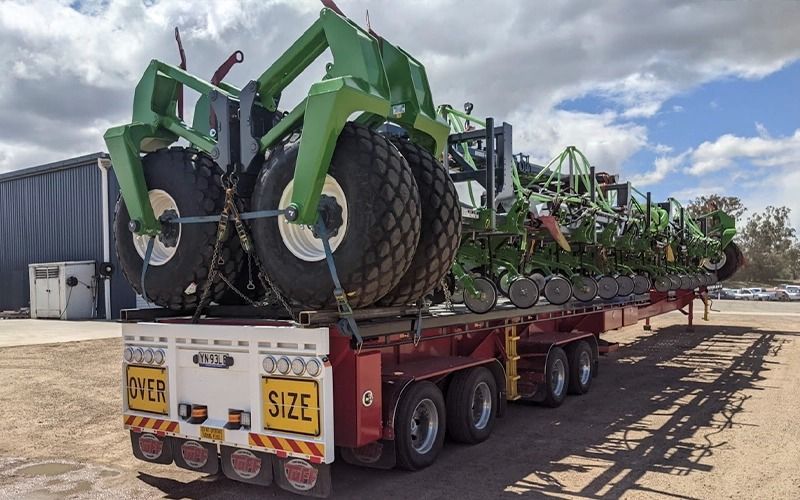 A large green farm implement loaded on an 