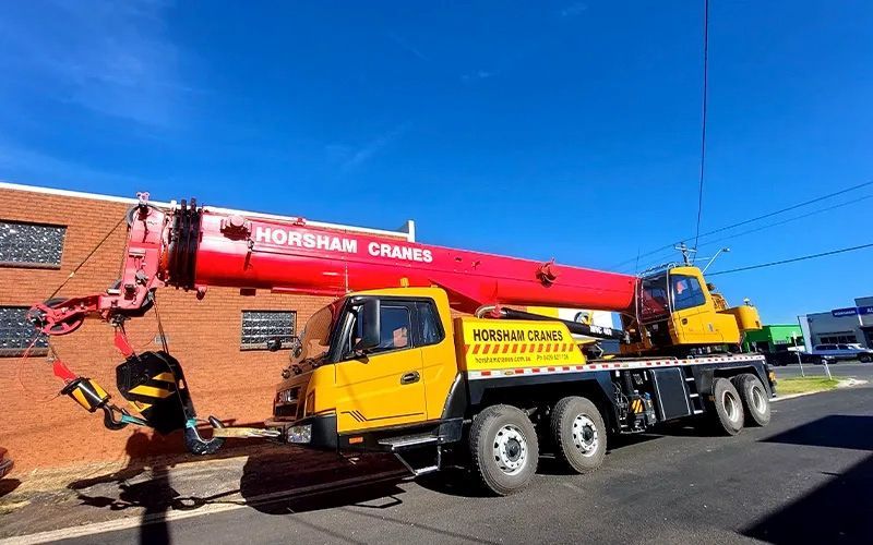 Large green farm machinery loaded on a red and white trailer, ready for transport.