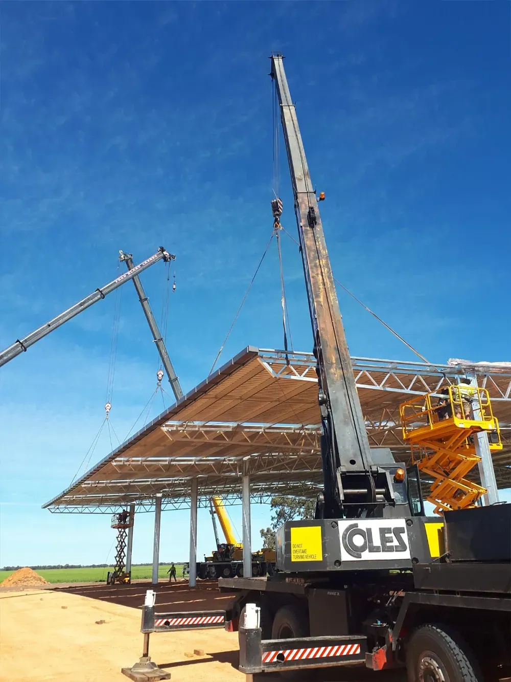 Construction site with a crane lifting materials, blue sky background.