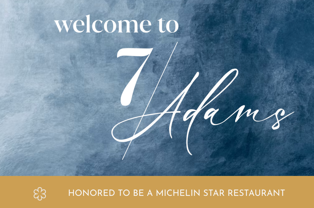 Blue welcome sign reading “Welcome to 7 Adams,” with gold banner: “Honored to be a Michelin star restaurant.”