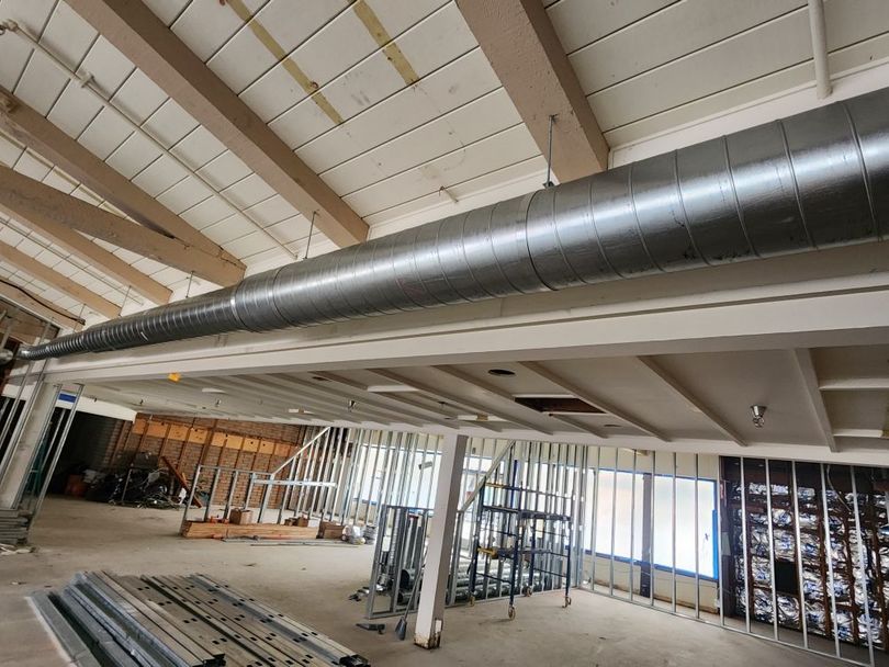 Unfinished interior with exposed ductwork, beams, and framing in a large open construction space