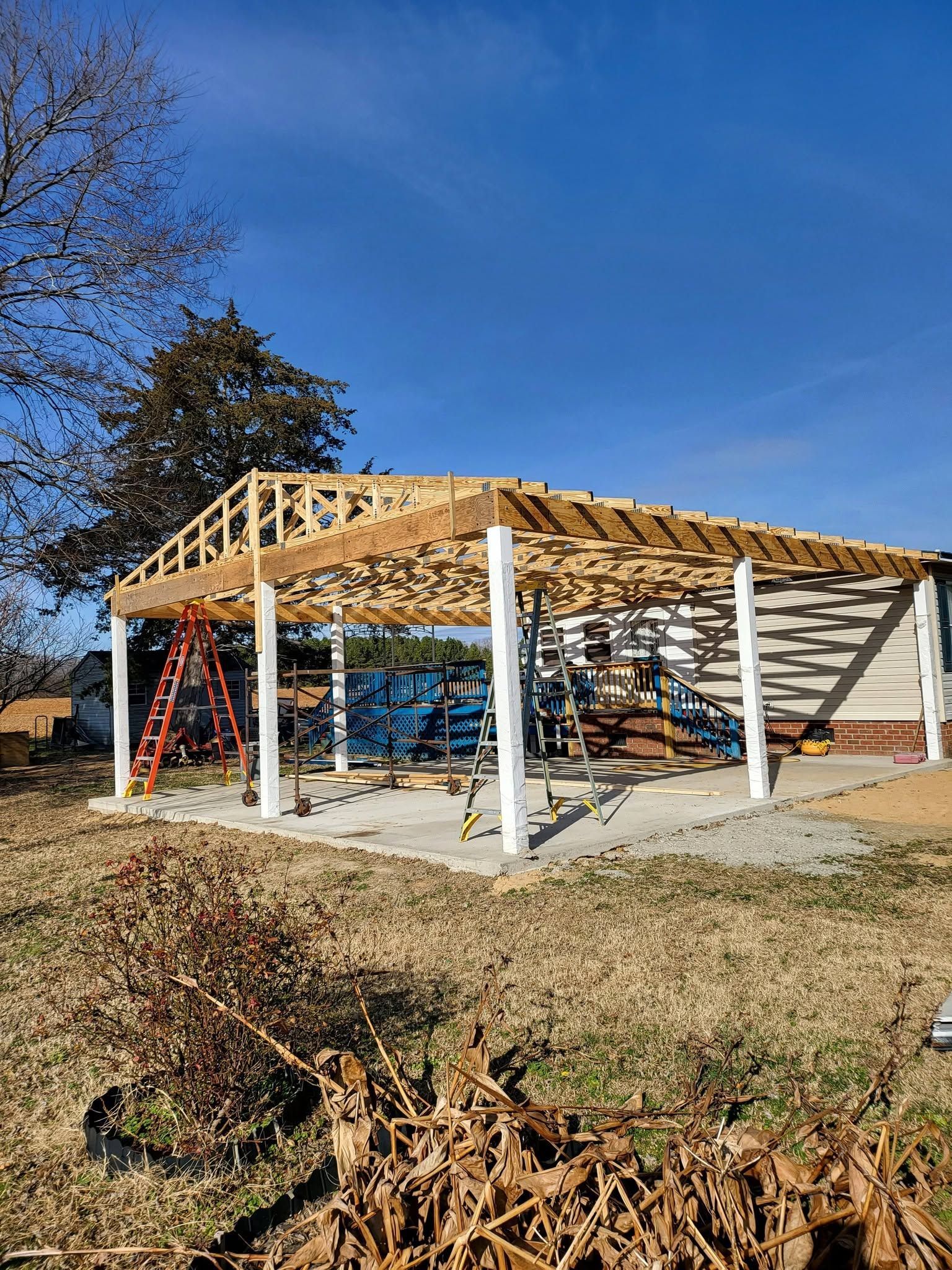 Open-sided wooden pavilion with a slanted roof in a sunny outdoor park setting