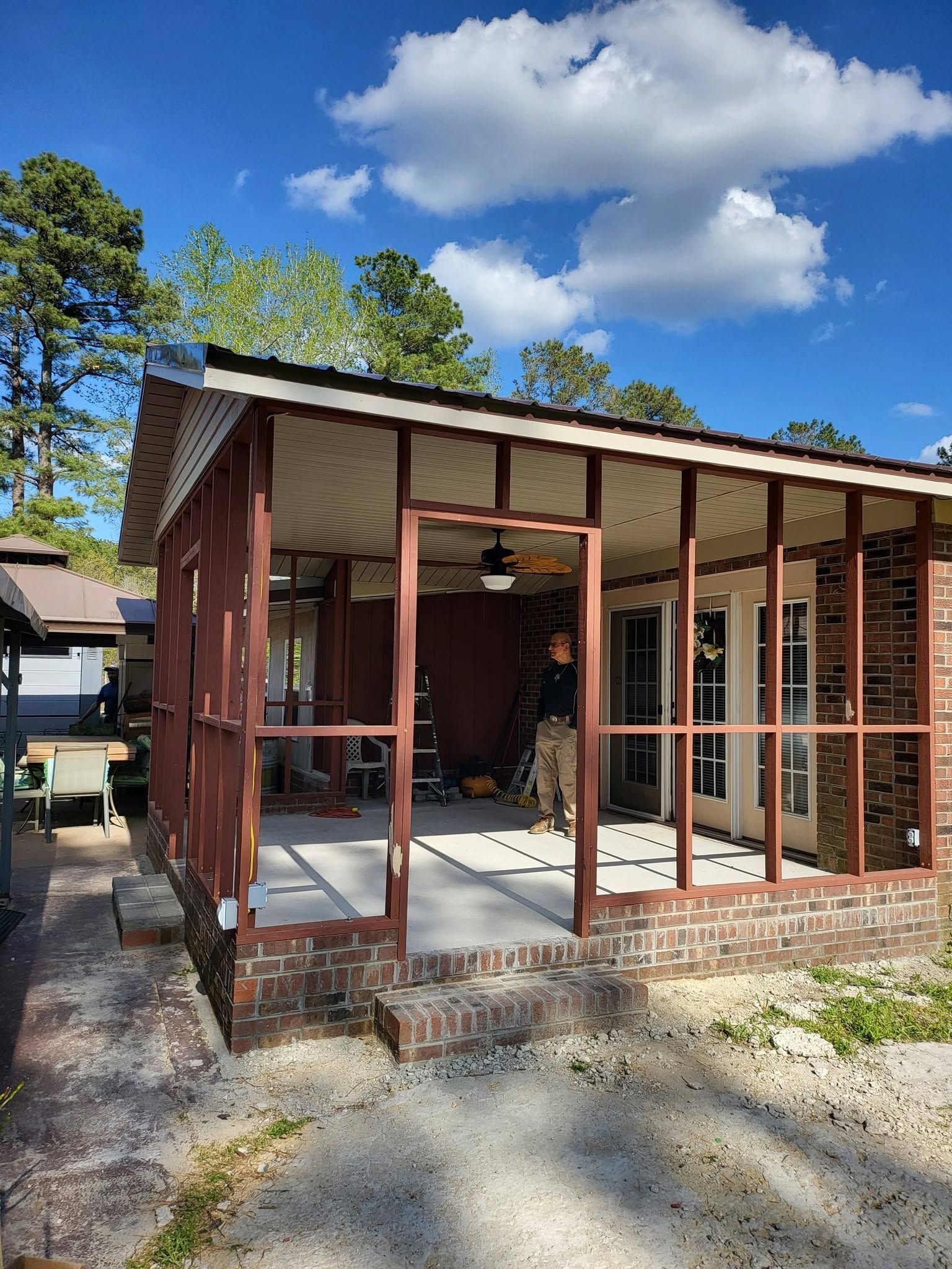 Partially built small wooden structure with exposed framing and a metal roof under a blue sky
