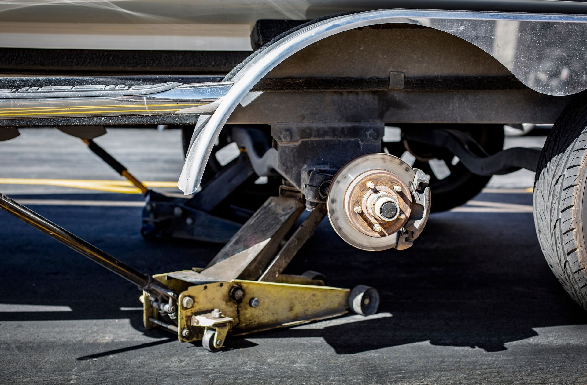 Close-up view of a car jack lifting a trailer that needs a new tyre. Close-up view of a car jack lifting a trailer that needs a new tyre.