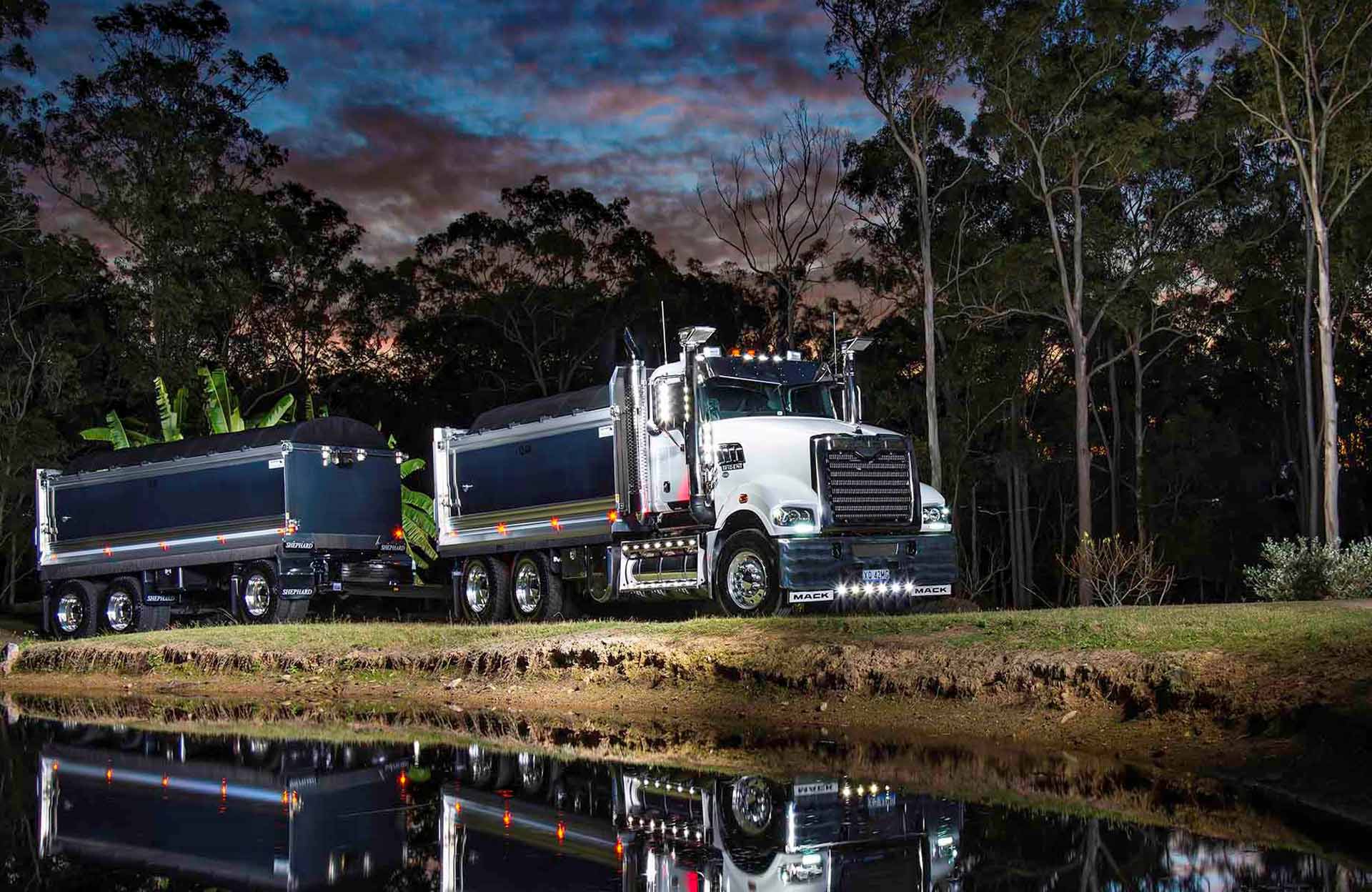 A dump truck is parked next to a body of water.