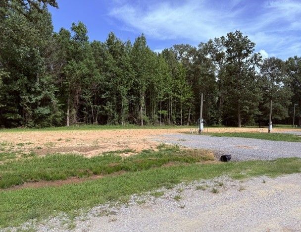 Spacious mobile home lot at Hickory Lane with mature trees and warm afternoon light