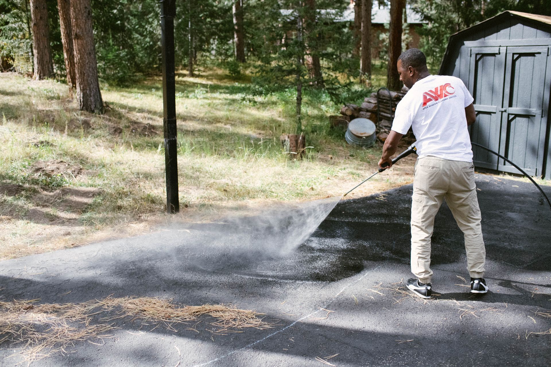 Person pressure-washing a wet concrete floor in black boots and jeans