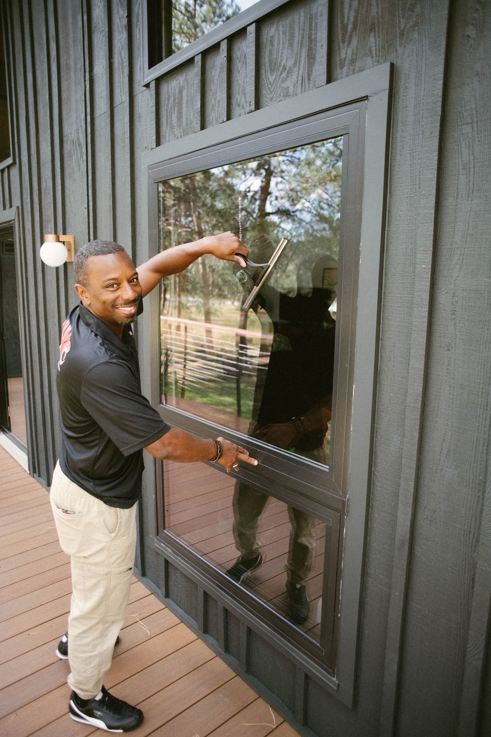 Person standing by a large window on a dark exterior wall, pointing at the glass.