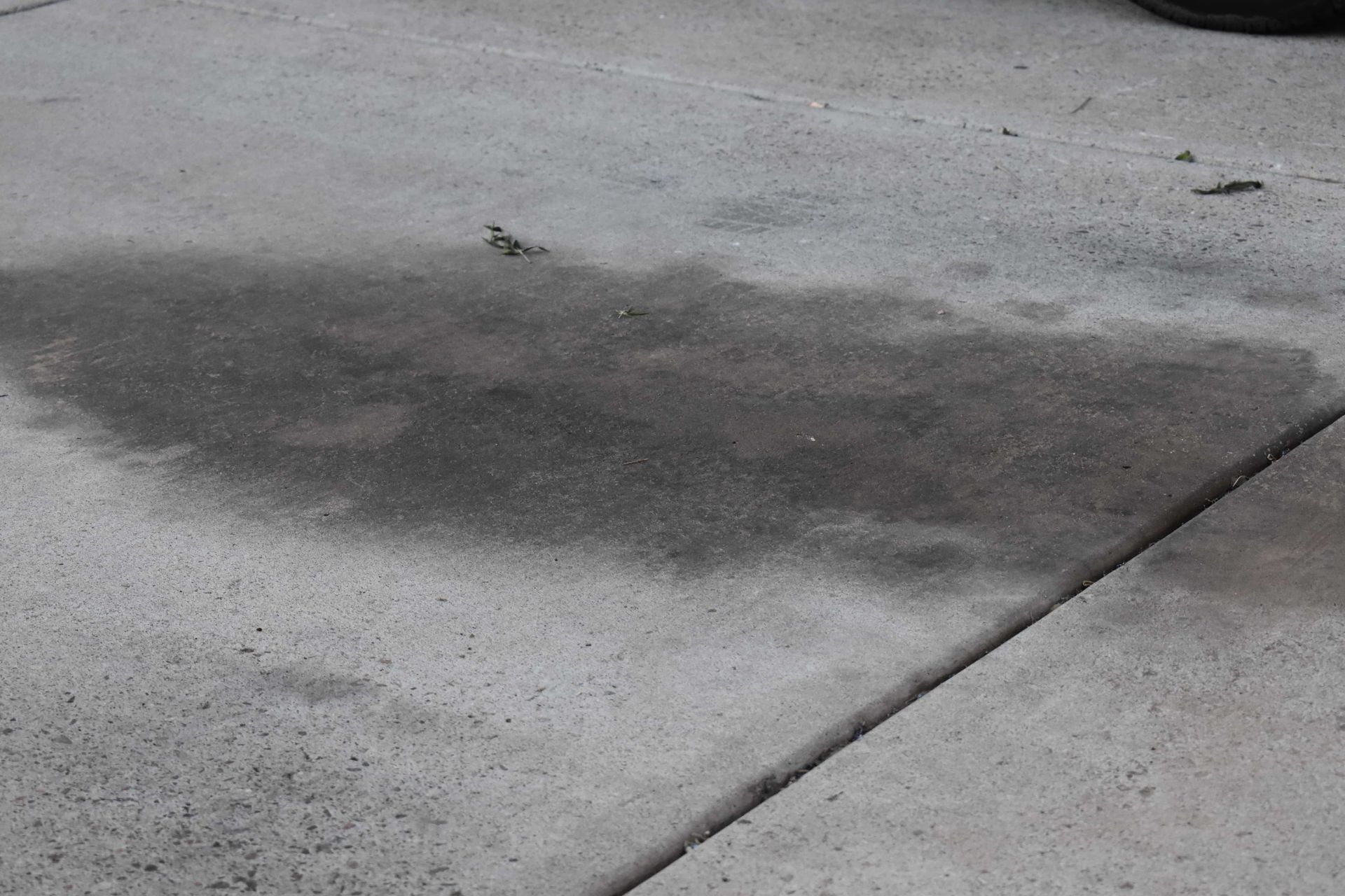 Dark oil stain on a concrete pavement slab near a joint line.