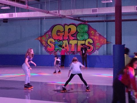 A group of people are rollerblading in front of a sign that says gr8 skates