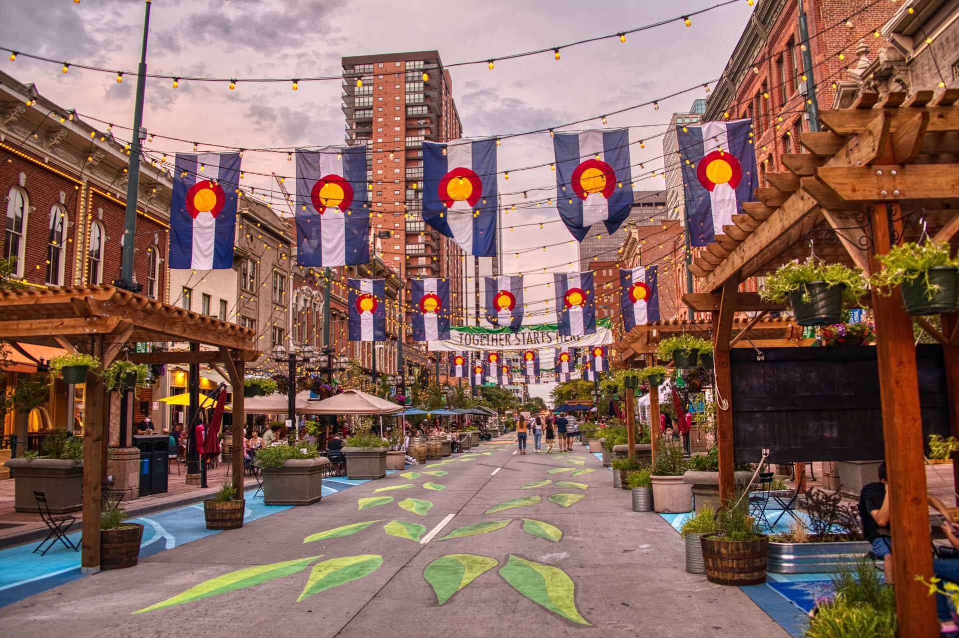 Festive pedestrian street with colorful lanterns, painted pavement, and brick buildings at dusk