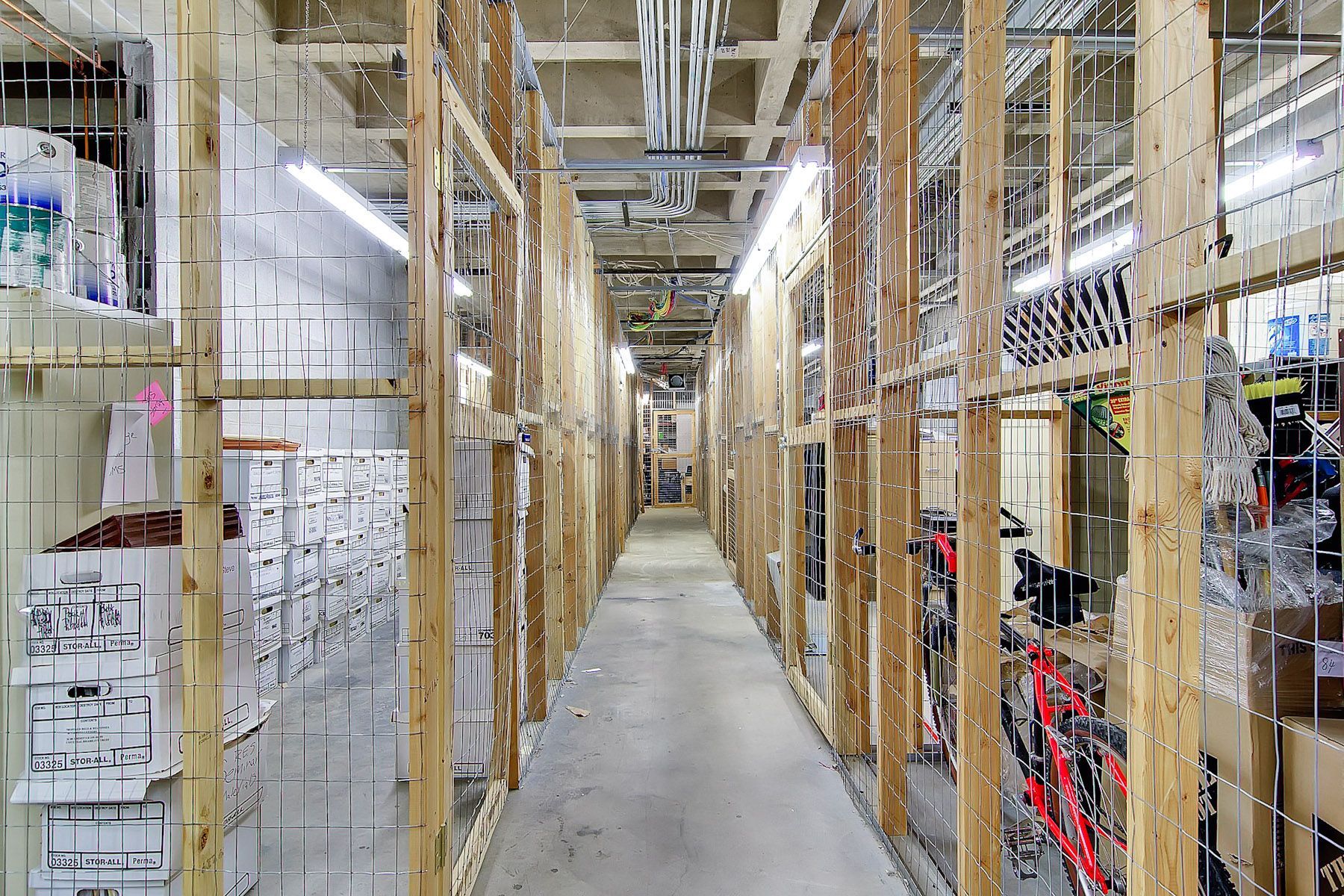 Long warehouse aisle lined with wooden racks, boxes, and industrial equipment