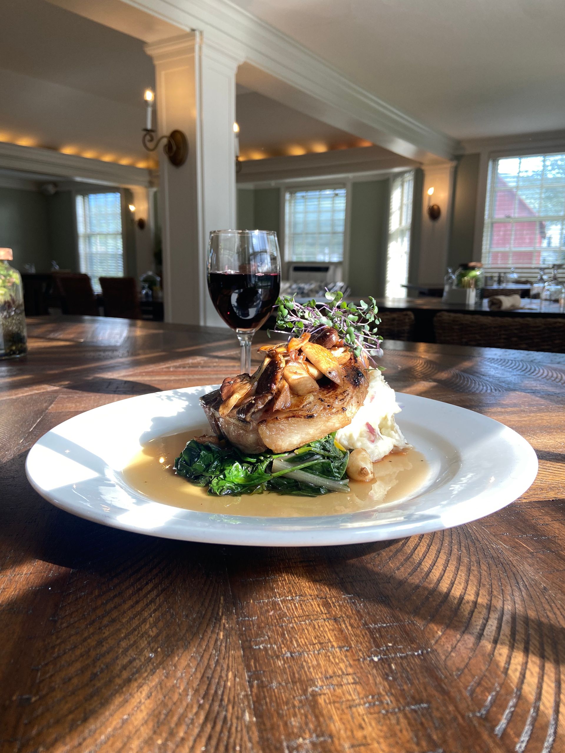 pork chop dish and glass of red wine in a dining room