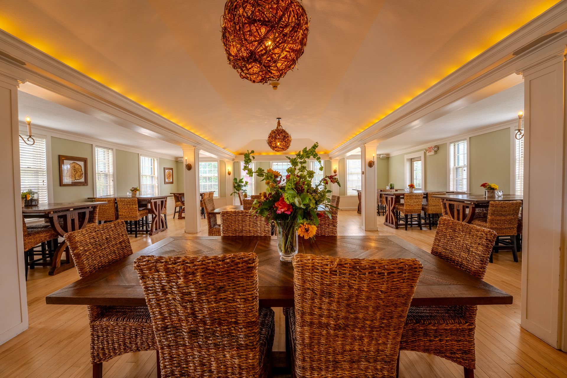 Franconia Inn dining room with wicker chairs and a table with a vase of flowers on it.