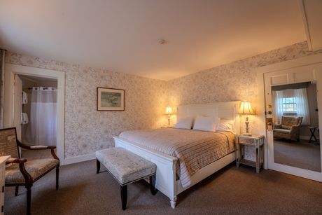 Bedroom with a large white bed, floral wallpaper, and a doorway to a sitting area.