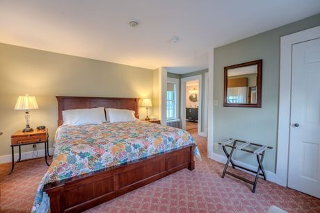 Bedroom with a wooden bed frame, floral bedding, two nightstands, and an open doorway to a bathroom.