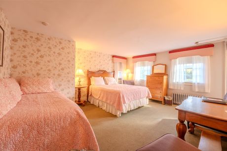 Cozy bedroom with floral wallpaper, a double bed, a twin bed, a desk, and a dresser. Pink and white decor.