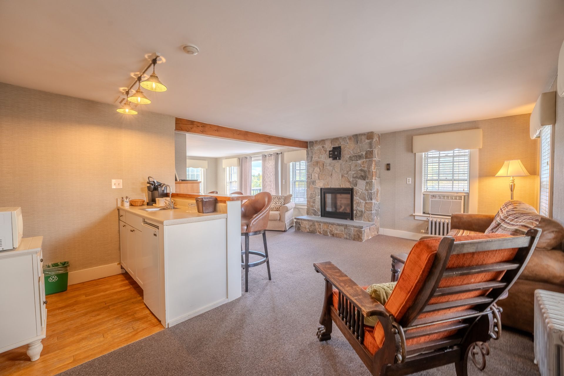 Cozy living space with stone fireplace, kitchen, and wooden armchair.