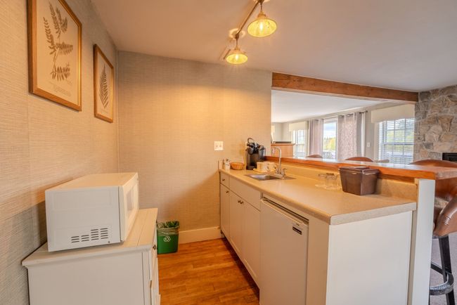 Bright kitchen with white cabinets, wooden floor, pendant lights, and a window over the sink