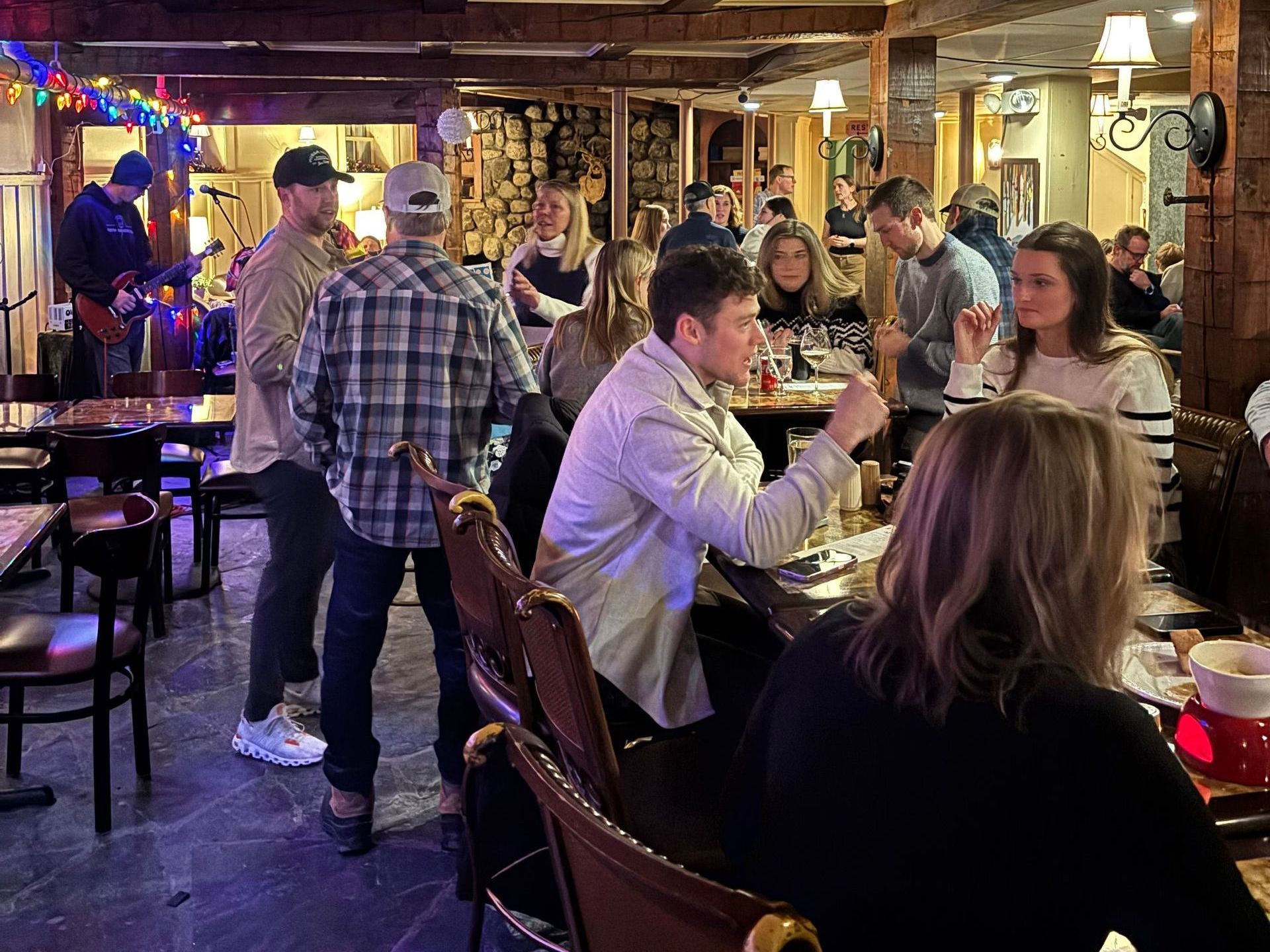 People at a crowded bar; a band plays. Dim lighting, wood interior.