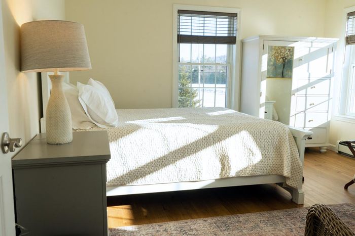 Bedroom with a bed, nightstand, lamp, and window with sunlight.