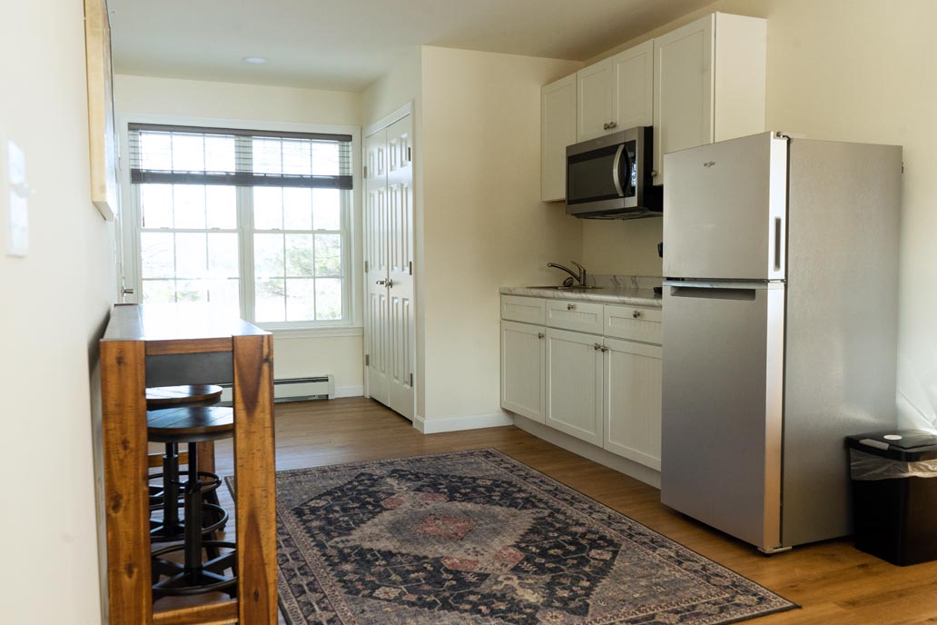 Small studio apartment with kitchen, dining table, and patterned rug.