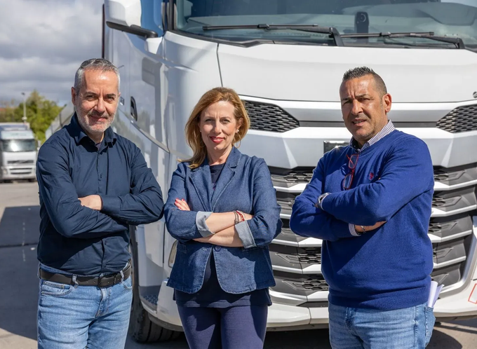 Tre persone in piedi con le braccia incrociate davanti a un camion bianco all'aperto