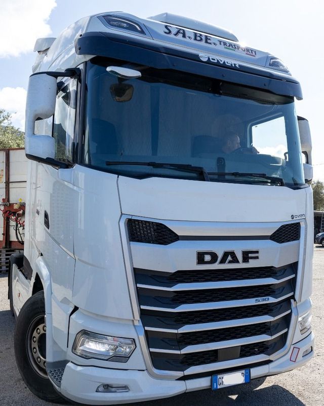 Un semirimorchio DAF bianco visto frontalmente su una strada, con parabrezza oscurato di blu e griglia cromata.